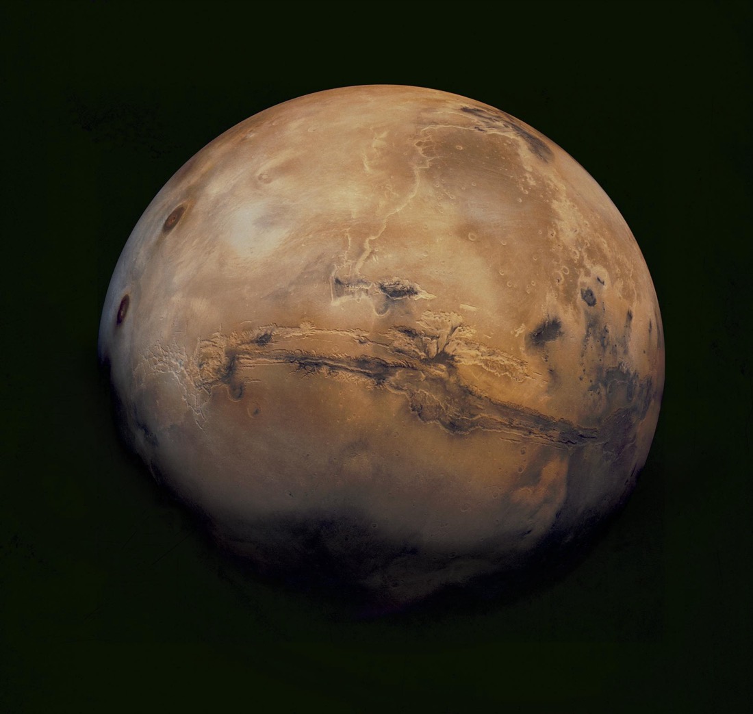 The full disc of Mars as a rust-red globe, its brighter southern highlands and darker markings visible, against black space.